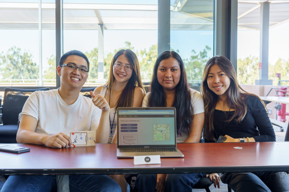 Zot Quest members behind a laptop displaying their project.